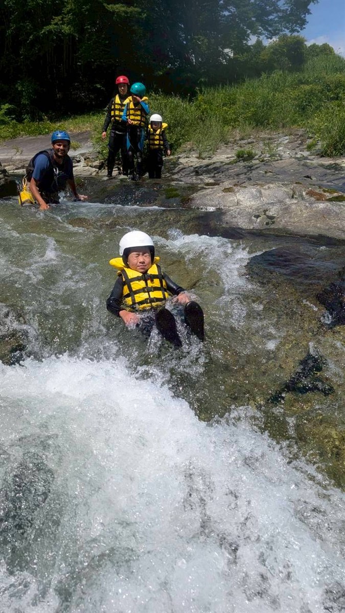 Kids enjoying family canyoning in Gunma on a natural water slide near Numata