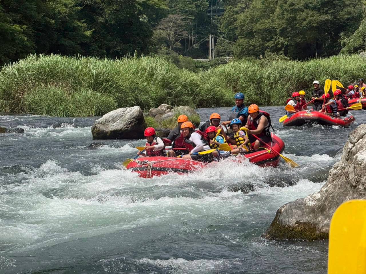 Family rafting in Japan on a clear summer river with kids and adults enjoying a guided rafting tour